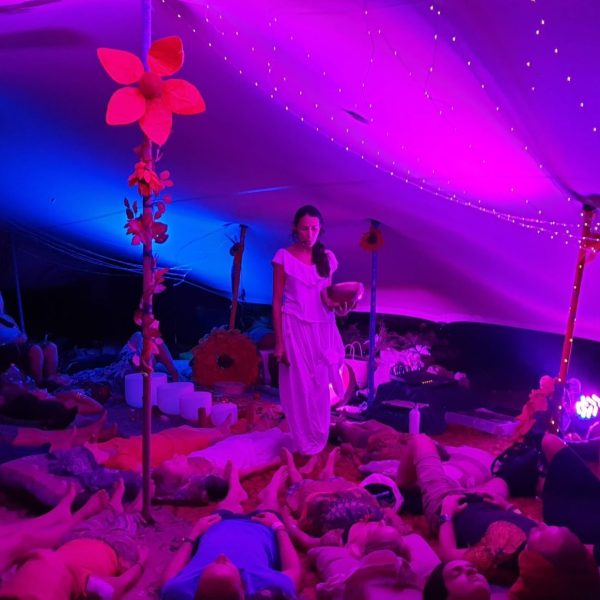 Carolina of Luminous Five guides a profound sound healing journey beneath an illuminated canopy, enveloping participants in sacred vibrations.